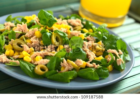 Fresh tuna, sweetcorn, green olive and watercress salad with orange juice in the back (Selective Focus, Focus in the middle of the salad)