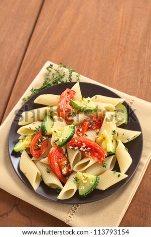 Vegetarian penne pasta dish with baked zucchini and tomato spiced with thyme and garlic (Selective Focus, Focus on the lower part of the dish)