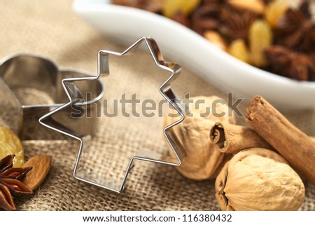Christmas tree cookie cutter with other baking ingredients (walnut, cinnamon, anise, raisin and almond) (Selective Focus, Focus on the upper part and right side of the cookie cutter)