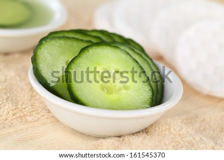 Cucumber slices used as natural moisturizer pads for the eyes in a bowl on towel (Selective Focus, Focus on the middle of the first cucumber slice)