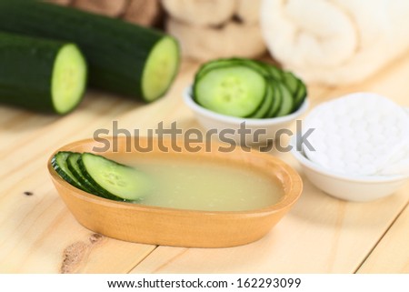 Homemade natural cucumber facial toner that hydrates, softens, soothes,cleanses the skin in a wooden bowl with cucumber slices (Selective Focus, Focus on the front of the cucumber slices in the toner)
