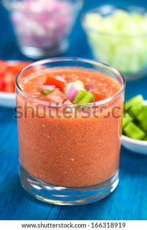 Traditional Spanish cold vegetable soup made of tomato,cucumber, bell pepper, onion, garlic and olive oil served in glass (Selective Focus, Focus on the front of the vegetables on the top of the soup)