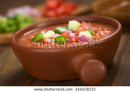 Spanish cold vegetable soup made of tomato, cucumber, bell pepper, onion, garlic and olive oil served in rustic bowl (Selective Focus, Focus on the front of the vegetables on the top of the soup)
