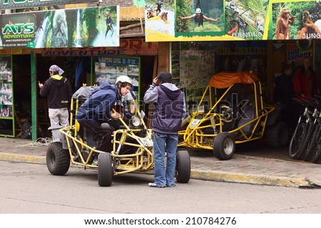 BANOS, ECUADOR - FEBRUARY 25, 2014: Unidentified people in and at a buggy in front of a tour operator and vehicle rental on 16 de Diciembre Street on February 25, 2014 in Banos, Ecuador.
