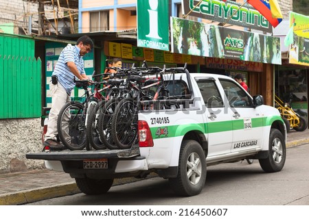 BANOS, ECUADOR - FEBRUARY 25, 2014: Unidentified man with mountain bikes on a pickup truck in front of a tour operator on 16 de Diciembre Street on February 25, 2014 in Banos, Ecuador