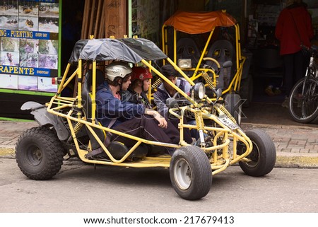 BANOS, ECUADOR - FEBRUARY 25, 2014: Unidentified people in a buggy in front of a tour operator and vehicle rental on 16 de Diciembre Street on February 25, 2014 in Banos, Ecuador.