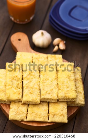 Fresh homemade garlic and cheese sticks made of a yeast dough served on wooden board (Selective Focus, Focus one third into the garlic sticks)