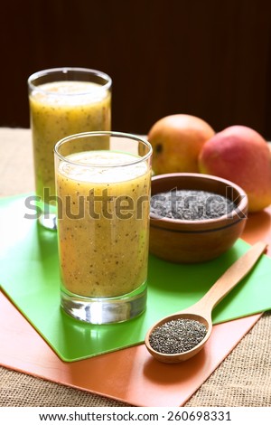 Chia seed (lat. Salvia hispanica) and mango juice photographed with natural light. Chia seeds are considered a superfood (Selective Focus, Focus on the front of the juice and the seeds on the spoon)