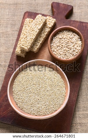 Overhead shot of raw white quinoa (lat. Chenopodium quinoa) grain seed, popped quinoa cereal, quinoa cereal bar on wood photographed with natural light (Selective Focus, Focus in middle of raw quinoa)