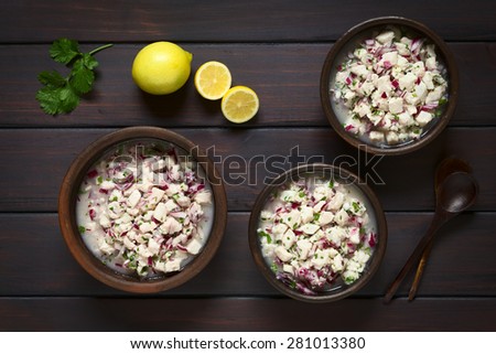 Chilean Ceviche made of Southern Ray\'s bream fish (lat. Brama Australis, Spanish Reineta), onion, garlic, cilantro in lemon juice in rustic bowls, photographed overhead on dark wood with natural light