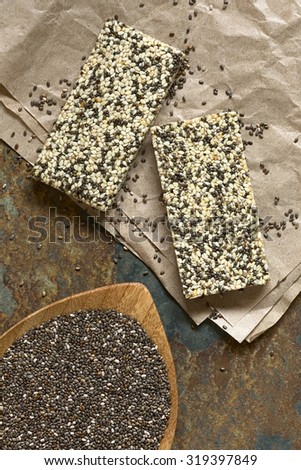 Chia seeds (lat. Salvia hispanica) and chia-sesame-honey granola bar, photographed overhead with natural light. Chia is considered a superfood containing protein, omega fat, minerals, antioxidants.