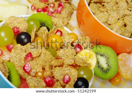 Fruits and cereals in colorful bowls on tablecloth