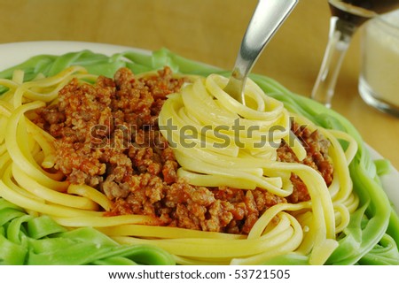 White and green spaghetti with bolognese sauce and spaghetti wrapped on fork (Selective focus)
