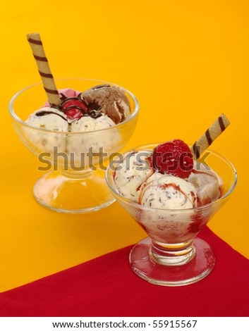 Ice-cream scoops in glass with syrup and wafer-rolls on red and orange