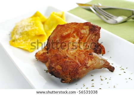 Main Dish: Guinea pig meat with ravioli on white rectangular plate with green table mat and cutlery in the background (Selective Focus)