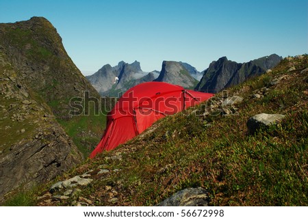 Red tent set up on a steep hillside on Moskenesoya, Lofoten, Norway