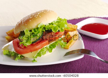 Hamburger with French fries, ketchup and fork on purple and white place mats (Selective focus)