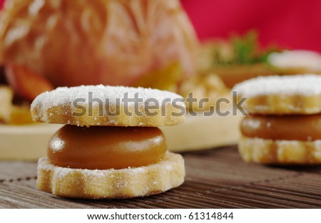 A Peruvian cookie called alfajor filled with manjar (a cream similar to caramel) on table mat with a baked apple in the background (Selective Focus)
