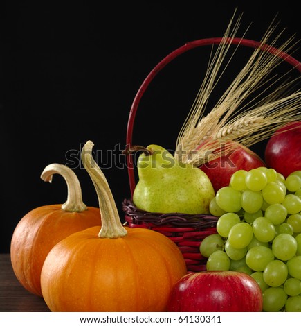An autumn basket with apple, pear, grapes, wheat and pumpkins (Selective Focus, Focus on apple, grapes and pumpkin in front)