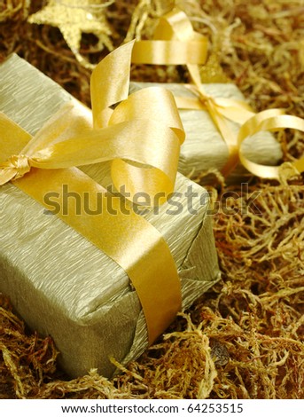 Boxes wrapped in golden paper with golden ribbon on brown moss (Selective Focus, Focus on front of the box)