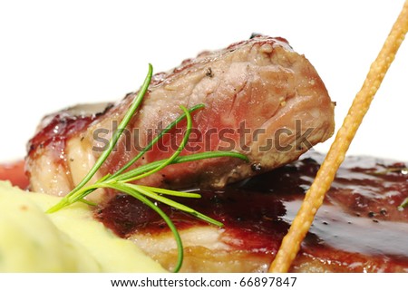 Fresh rosemary and red meat with red gravy and mashed potatoes in the foreground (Selective Focus, Focus on the rosemary and the front of the meat)