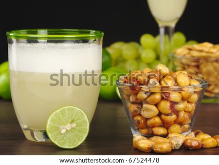 The Peruvian cocktail, Pisco Sour with the Peruvian snack, roasted corn, called cancha and grapes, limes, Pisco Sour and habas (roasted beans) in the background (Selective Focus, Focus on the front)