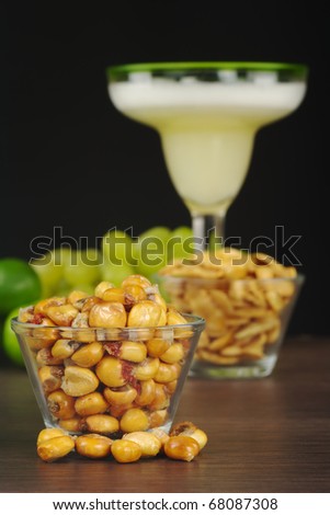 Canchas: Peruvian roasted corn eaten as snack with the cocktail called Pisco Sour in the back with limes and grapes (Selective Focus, Focus on the front)