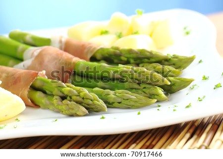 Green asparagus with ham and potatoes (Selective Focus, Focus on the asparagus heads in the front)