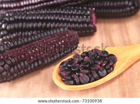 Peruvian purple corn grains on wooden spoon (Selective Focus, Focus on the grains)