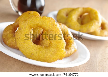 Popular Peruvian dessert called Picarones made from squash and sweet potato, served with Chancaca syrup (kind of honey), on plastic plate (Selective Focus, Focus on the front)