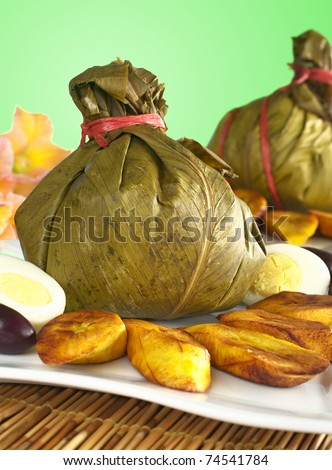 Traditional Peruvian food called Juane from the jungle area, in which rice, eggs and meat is wrapped into bijao leaves, served with fried plantains, eggs (Selective Focus, Focus on front)