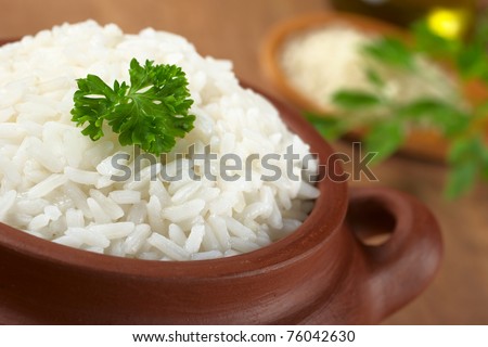 Cooked white rice garnished with parsley in a rustic bowl (Selective Focus, Focus on the parsley and the rice around)