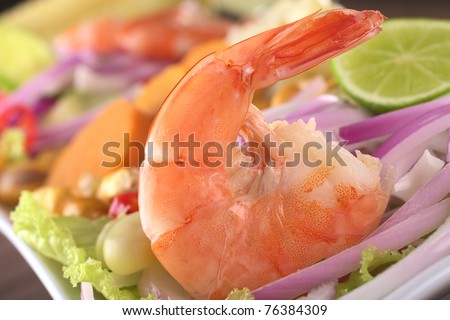 Peruvian Prawn Ceviche: King prawn on red onions and lettuce with corn grains, lime slices and sweet potato in the back (Selective Focus, Focus on the prawn)