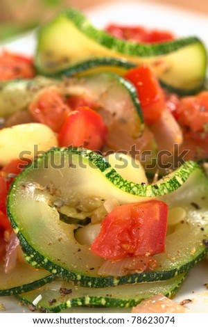 Sauteed zucchini slices, tomato cubes, onion and cooked corn grains with dried herbs and black pepper (Selective Focus, Focus on the upper part of the zucchini slice and the tomato cube below)