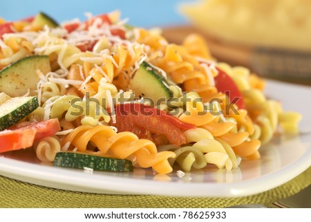 Colorful fusilli pasta with zucchini, tomato and grated cheese (Selective Focus, Focus on the tomato in front)