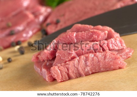 Fresh raw beef meat with knife and pepper corns in the back (Selective Focus, Focus on the front of the beef)