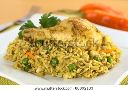 Peruvian dish called Arroz con Pollo, which is made of rice, chicken parts, peas, corn, aji (hot pepper), cilantro (Selective Focus, Focus on the right front part of the chicken thigh)