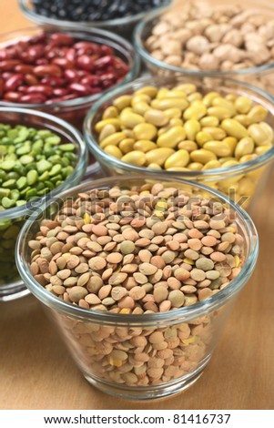 Lentils and other legumes (split peas, canary beans, kidney beans, chickpeas) in glass bowls (Selective Focus, Focus one third into the lentils)