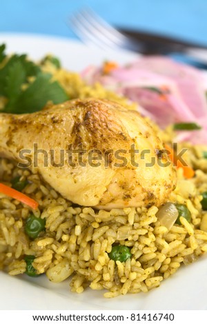 Peruvian dish called Arroz con Pollo (Rice with Chicken), made of rice, chicken, pea, corn, aji (hot pepper), cilantro (onion salad) (Selective Focus, Focus on the front of the chicken thigh)