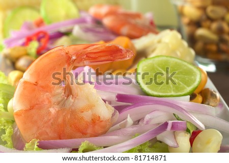 Peruvian Prawn Ceviche: King prawn on red onions and lettuce with corn grains and lime slices in the back (Selective Focus, Focus on the prawn)