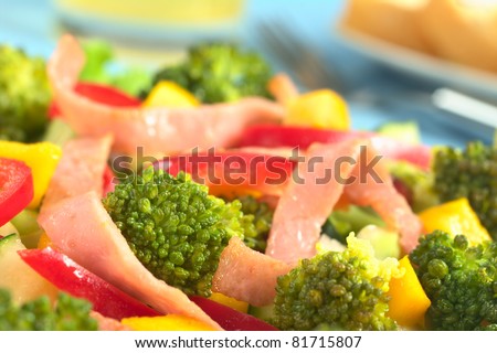 Fresh broccoli salad with red bell pepper, ham and mango (Selective Focus, Focus on the broccoli floret in the left lower part)