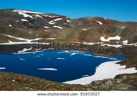 Lake surrounded by barren and partly snow covered mountains close to Sulitjelma in Northern Norway