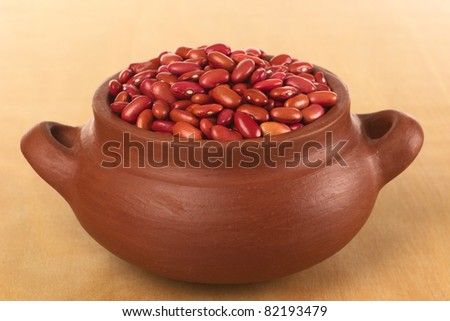 Raw red kidney beans in rustic bowl photographed on wood (Selective Focus, Focus on the beans in the front of the bowl)