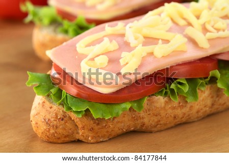 Open sandwich with lettuce, tomato, cheese, ham and grated cheese on top (Selective Focus, Focus on the front edge of the sandwich)