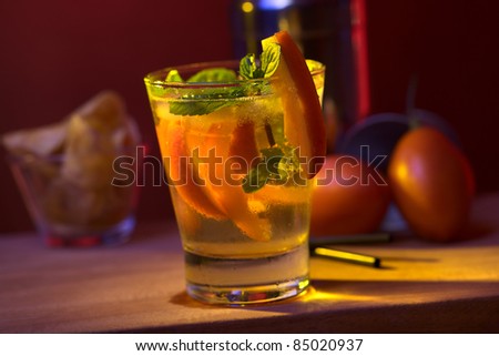 Tamarillo cocktail (Selective Focus, Focus on the front of the glass, the mint leaf and the tamarillo garnish)