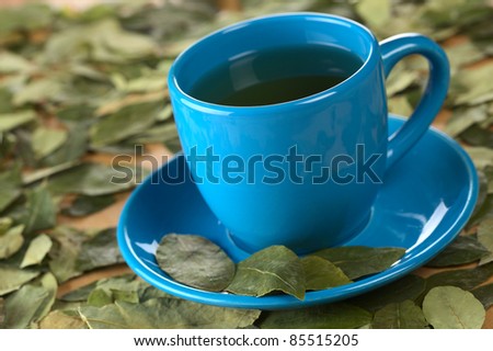 Popular Peruvian herbal tea made of dried coca (lat. Erythroxylum coca) leaves (Selective Focus, Focus on the front rim of the cup and the front of the second from left coca leaf on the saucer)