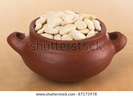 Raw lima beans (butter beans) in rustic bowl photographed on wood (Selective Focus, Focus on the beans in the front of the bowl)