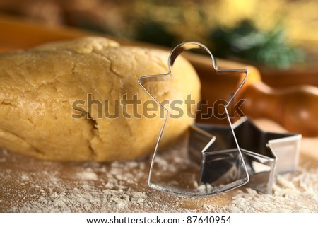 Angel-Shaped cookie cutter with cookie dough and rolling pin in the back (Selective Focus, Focus on the angel-shaped cutter)