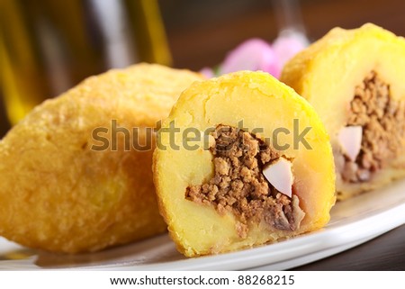 Peruvian dish called Papa Rellena (Stuffed Potato) made of mashed potatoes and filled with meat and egg (Selective Focus, Focus on the front of the half papa rellena)