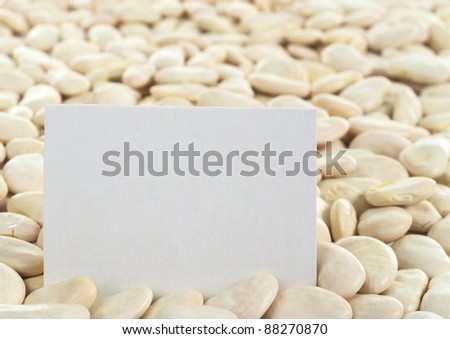 Dried raw butter bean or also called lima bean (lat. Phaseolus lunatus) with a blank card (Selective Focus, Focus on the card)
